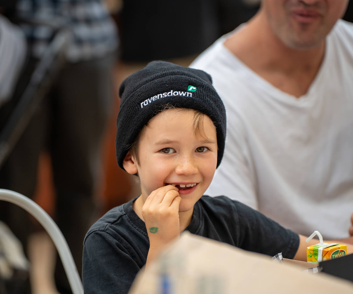 Mystery Creek 2025, National Field Days, Kid With Ravensdown Beanie Smiling And Eating Kids Meal
