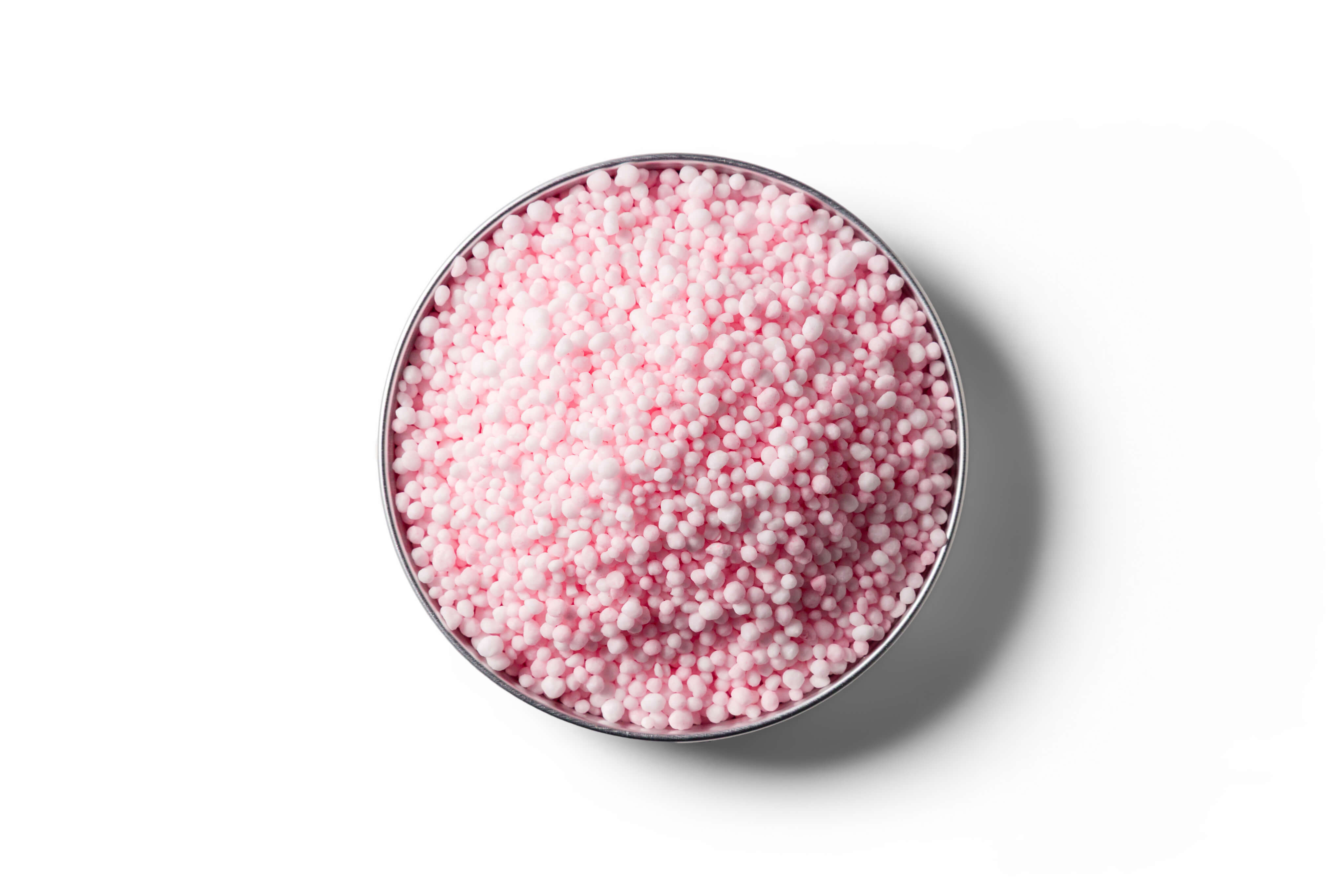 Pink N-Protect coated urea fertiliser granules in a round dish