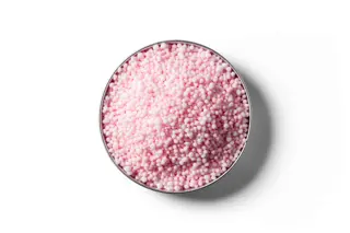 Pink N-Protect coated urea fertiliser granules in a round dish